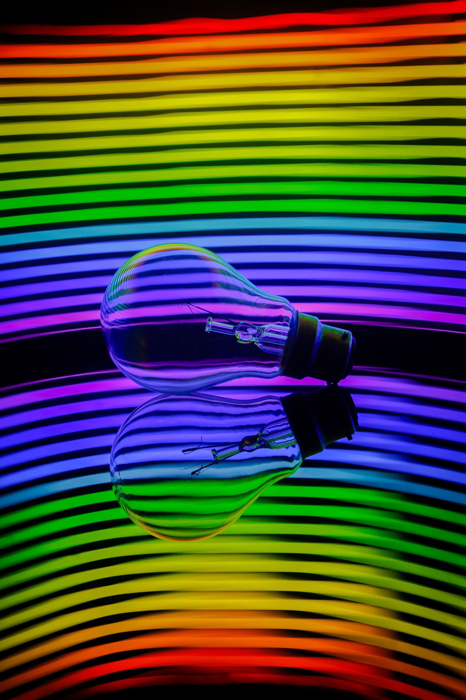 Light bulb reflecting a rainbow spectrum of coloured light
