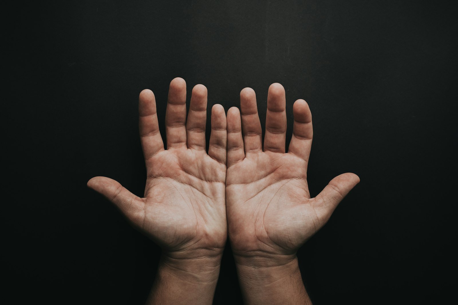 Open palms of two hands against a dark background
